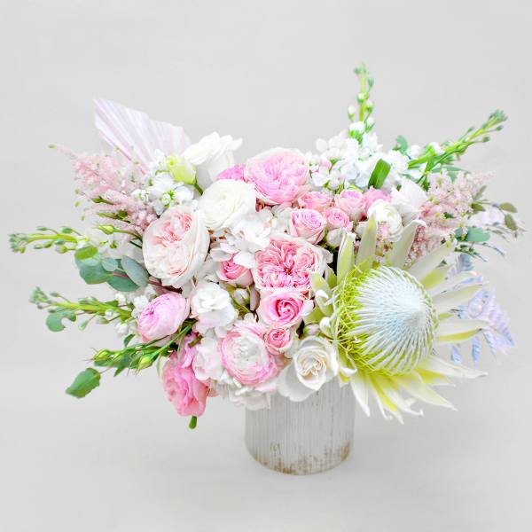 Pink and white bouquet in a white vase with a large pale protea bloom