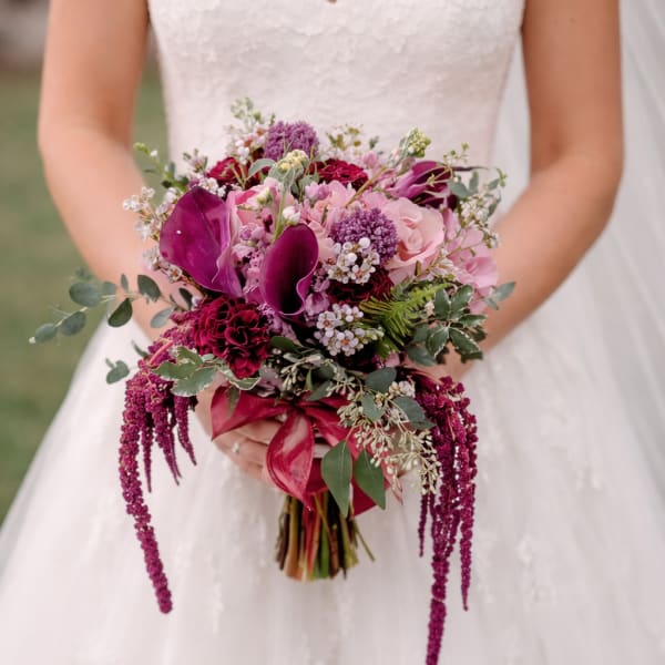 Bride holding a cascading bouquet of pink and burgundy flowers