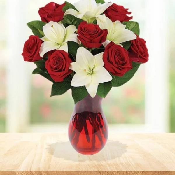 Red roses and white lilies arranged in a red glass vase