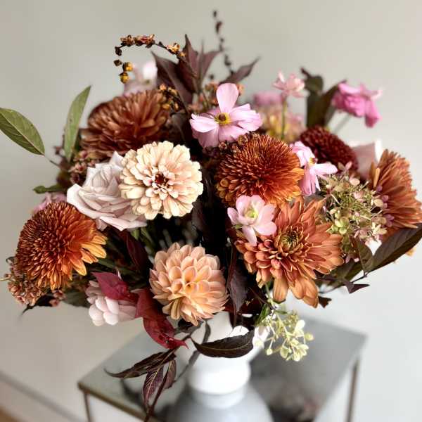 Bouquet of orange, pink, and cream flowers in a white vase