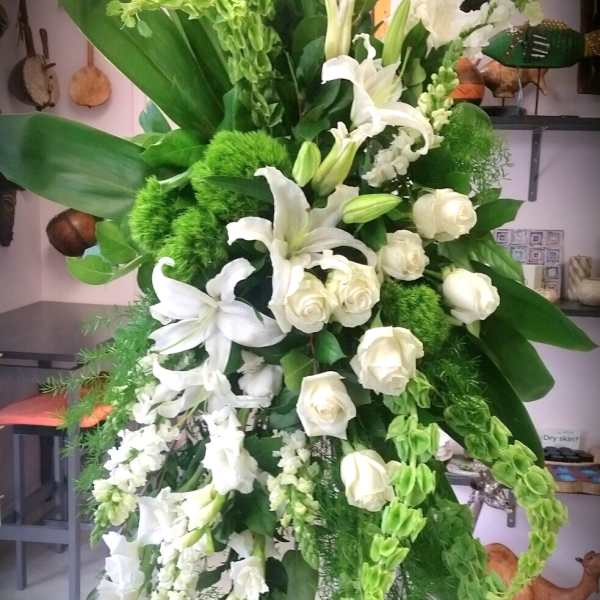 Tall white floral standing spray with lilies and roses on a metal easel