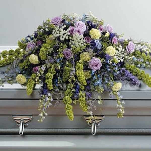 Lavender and white floral casket spray with trailing blooms