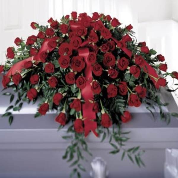 Large red rose casket spray with ribbon on a gray casket