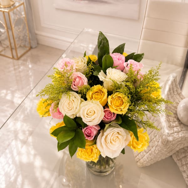 Bouquet of pink, white, and yellow roses in a clear glass vase