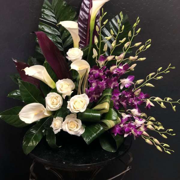 Arrangement of white calla lilies, cream roses, and purple orchids
