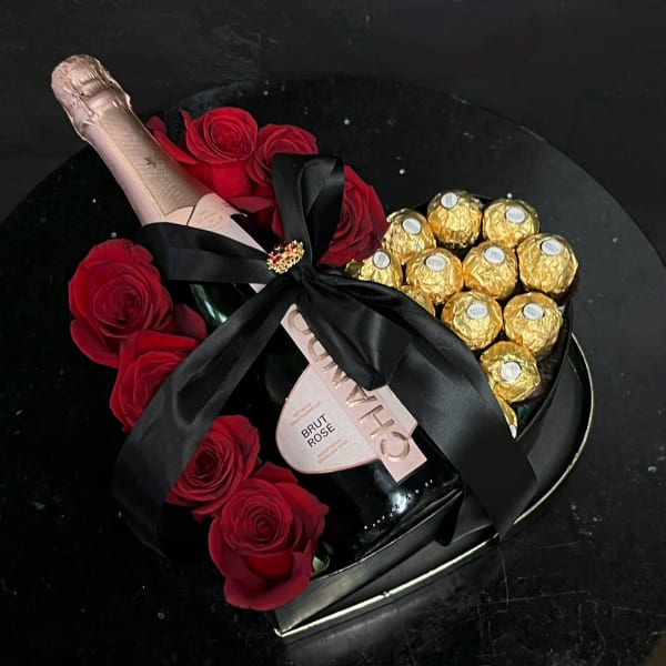 Heart-shaped gift box with red roses, champagne, and gold-wrapped chocolates
