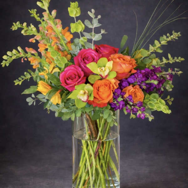 Colorful bouquet of roses, orchids, and snapdragons in a clear glass vase