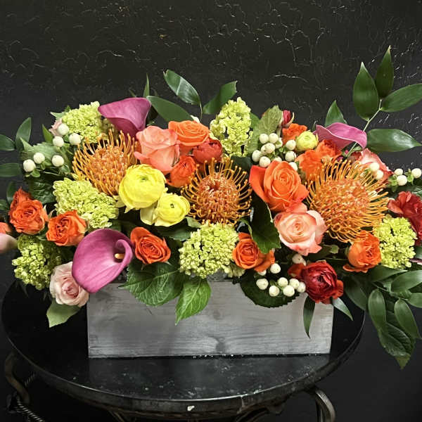 Colorful floral arrangement in a gray rectangular box with pink calla lilies and roses