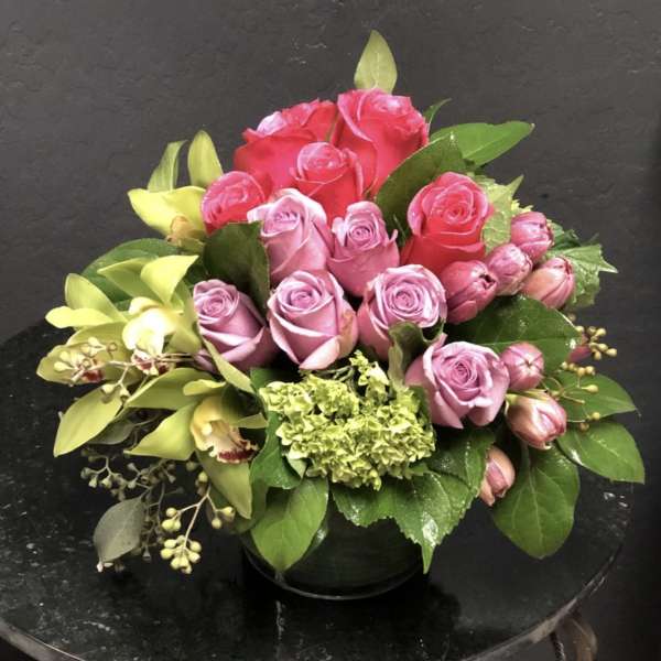 Pink and red rose bouquet with green hydrangea in a black vase
