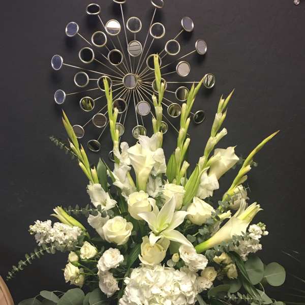 White floral arrangement in a glass vase with tall blooms and greenery