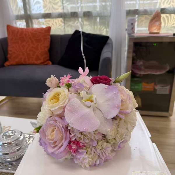 Round pastel bouquet with roses, orchids, and hydrangeas on a white box