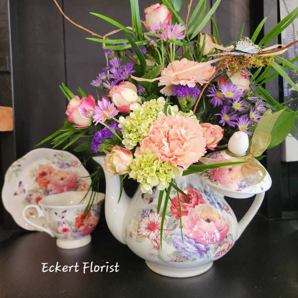Floral arrangement in a floral teapot with pink, purple, and green blooms