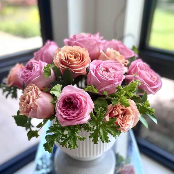 Pink and peach roses arranged in a white vase