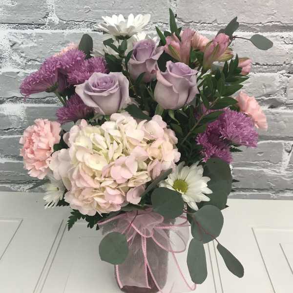 Pink and lavender bouquet in a glass vase with white daisies