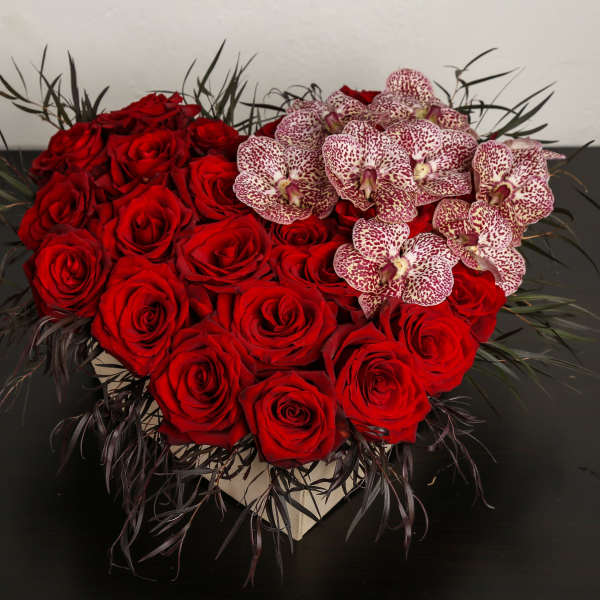 Heart-shaped arrangement of red roses with spotted orchids