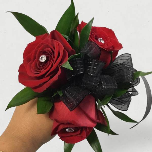 Handheld bouquet of red roses with black ribbon and green leaves