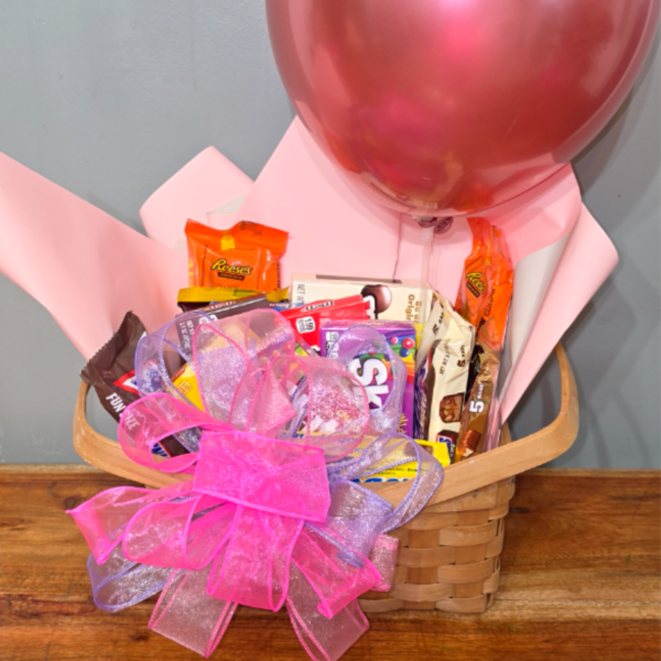 Basket of assorted candy with a pink balloon and ribbon bow