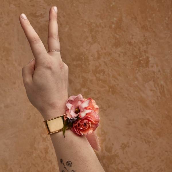 Wrist corsage with pink and coral flowers on a gold cuff bracelet