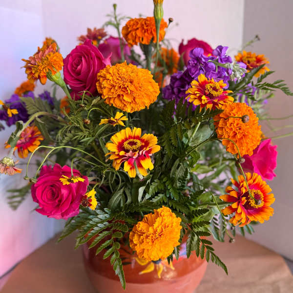 Bright mixed bouquet with pink roses and orange marigolds in a vase