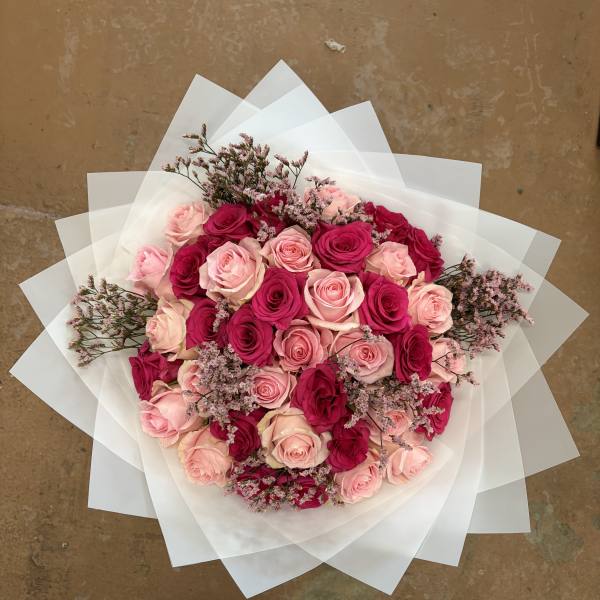 Bouquet of pink and hot pink roses wrapped in white paper