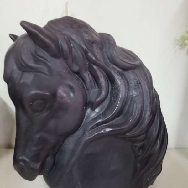 Black horse head sculpture on a white surface