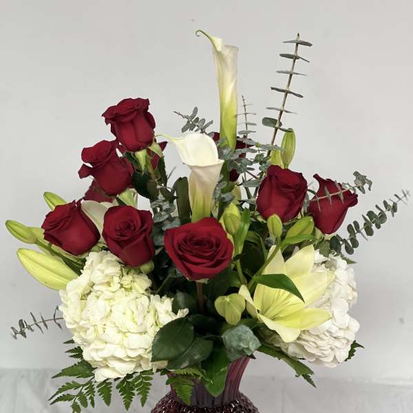 Red roses and white calla lilies in a burgundy vase