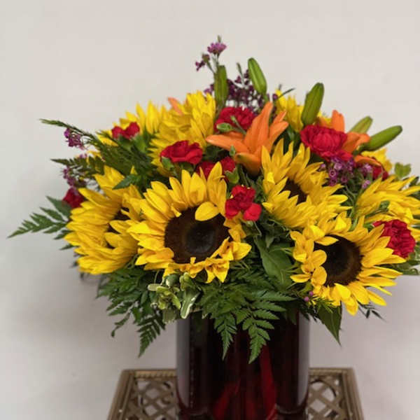 Bouquet of sunflowers, red roses, and orange lilies in a dark vase
