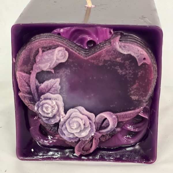 Purple square candle with a heart-shaped floral decoration