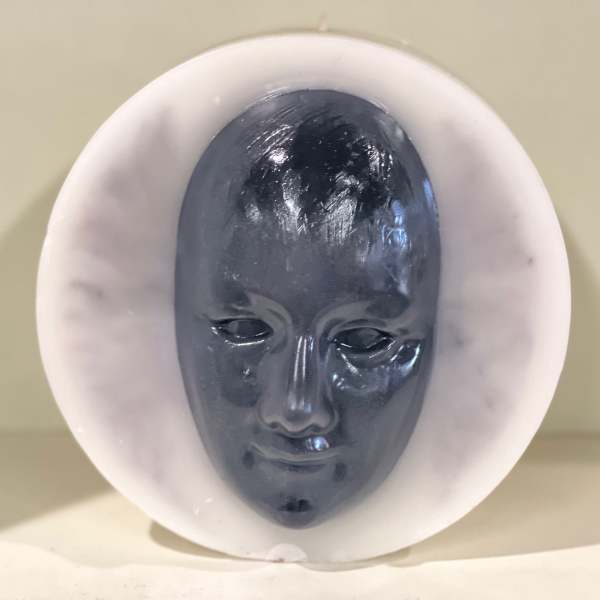 Dark sculpted face inside a white circular frame