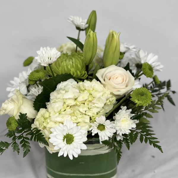 White and green floral arrangement in a square glass vase