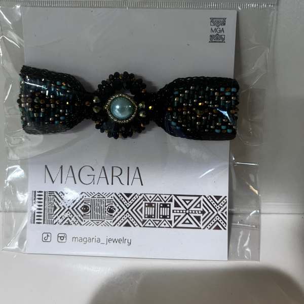 Beaded black bow hair accessory in plastic packaging