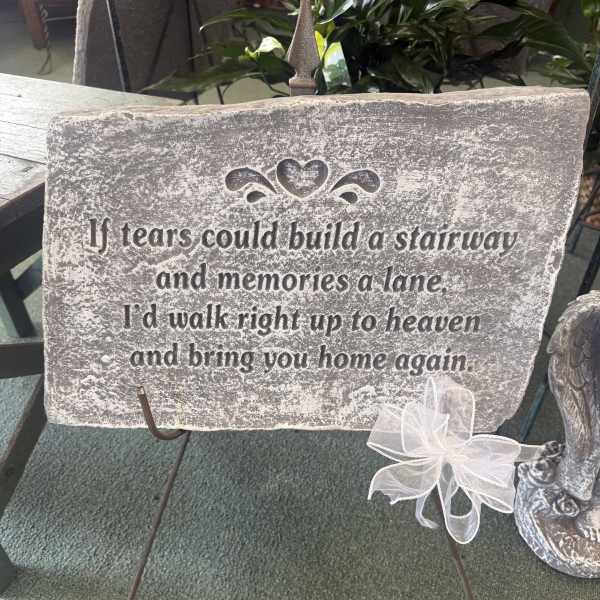 Memorial stone sign on a metal stand with a white ribbon bow