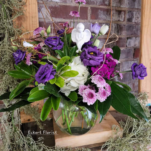 Purple and white flowers arranged in a clear glass vase