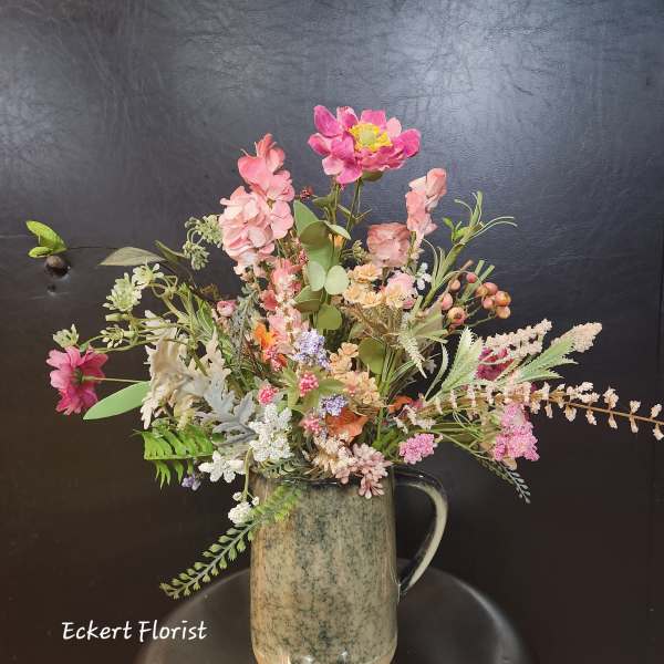 Mixed pink floral arrangement in a ceramic pitcher vase
