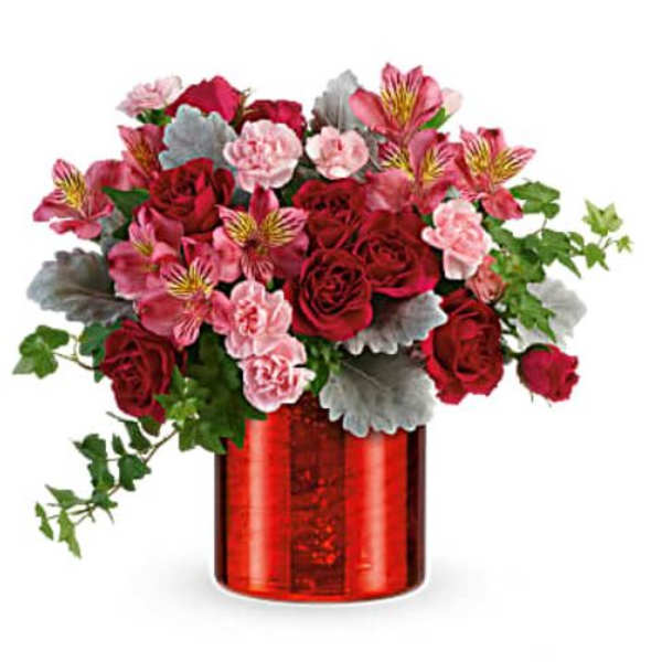 Red and pink flower arrangement in a red glass vase
