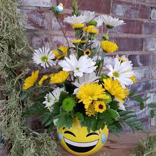 Yellow and white daisy bouquet in a smiley-face pot