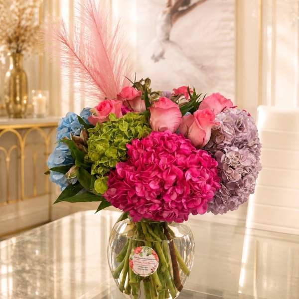 Colorful bouquet of hydrangeas and pink roses in a clear glass vase