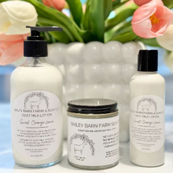 Tulips behind three goat milk skincare products on a white surface
