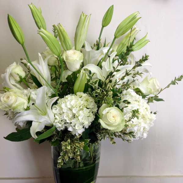 White lilies and roses arranged in a clear glass vase