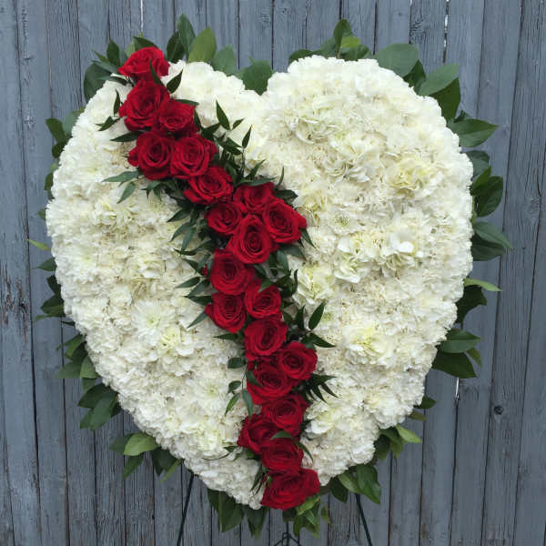 Heart-shaped white floral arrangement with a diagonal line of red roses