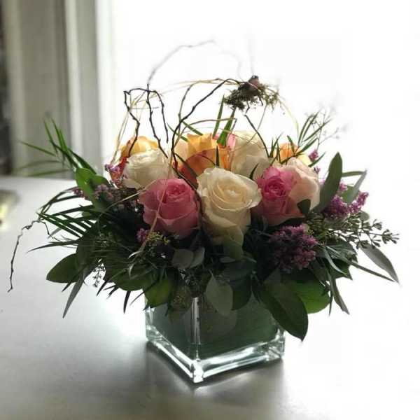 Pink and white roses arranged in a square glass vase