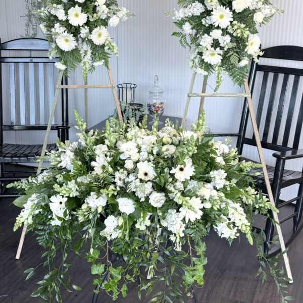 White floral funeral display with two standing sprays and a low arrangement