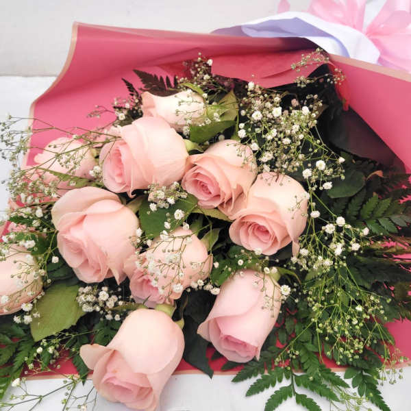 Bouquet of pale pink roses with baby's breath in pink wrapping