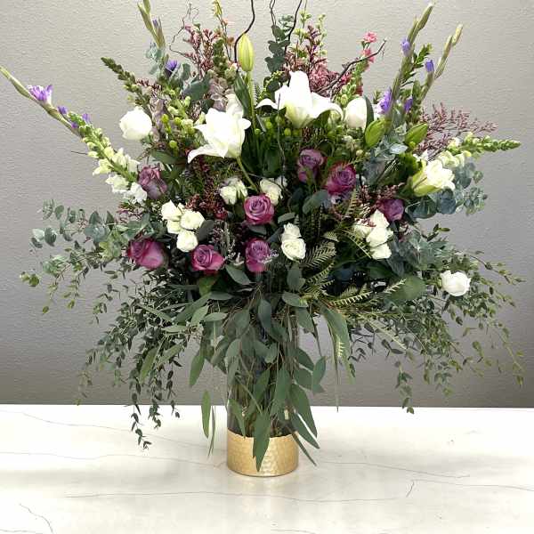 Tall floral arrangement with white lilies and pink roses in a gold vase