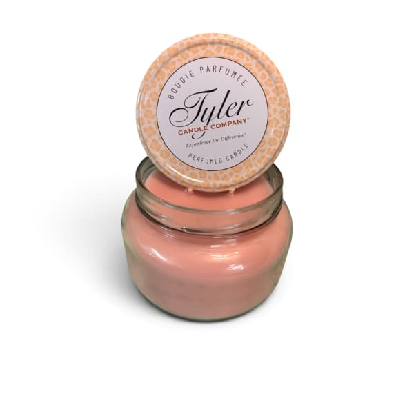 Pink scented candle in a glass jar with a patterned lid