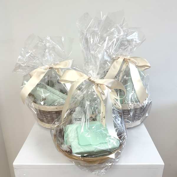 Three wrapped gift baskets with cream ribbons on a white surface