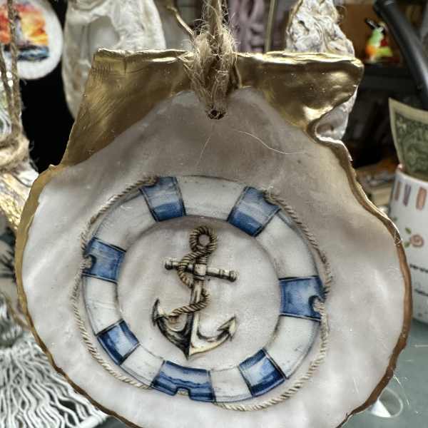Decorative hanging ornament shaped like a shell with an anchor design