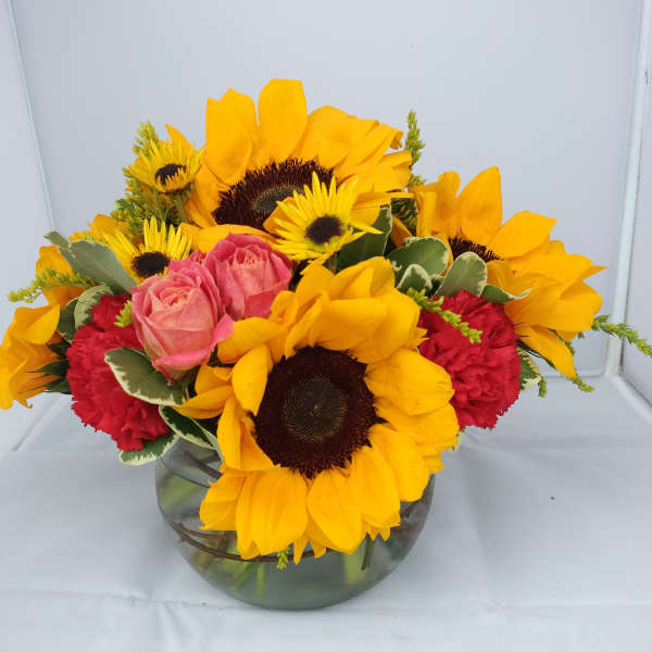 Sunflowers and pink roses arranged in a glass vase