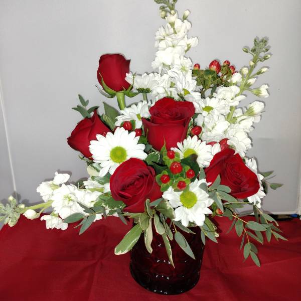Red roses and white daisies in a dark glass vase