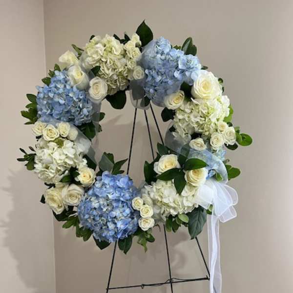 Blue and white floral wreath on a stand with a white ribbon